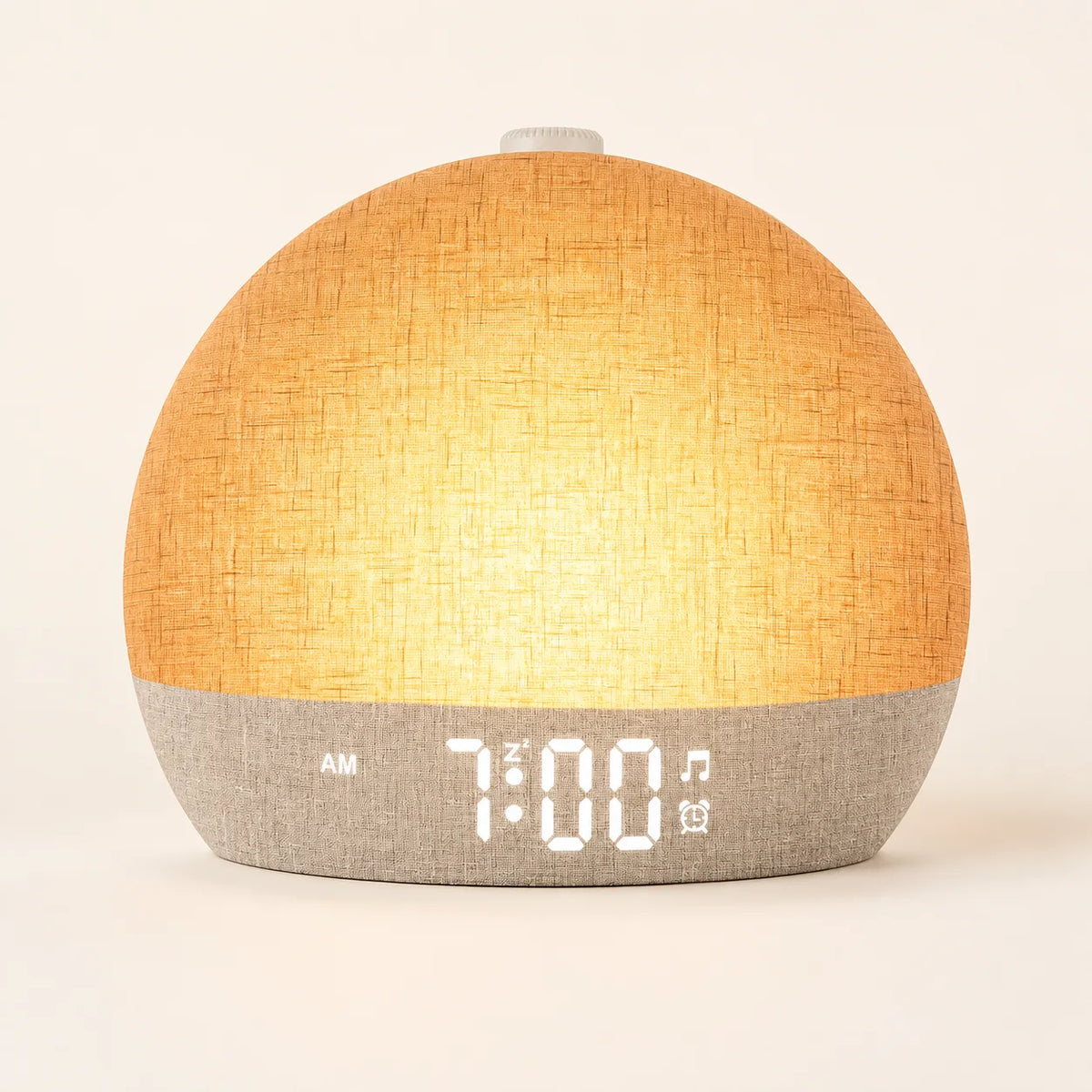 Linen-textured sunrise alarm clock glowing amber on an ivory studio background.