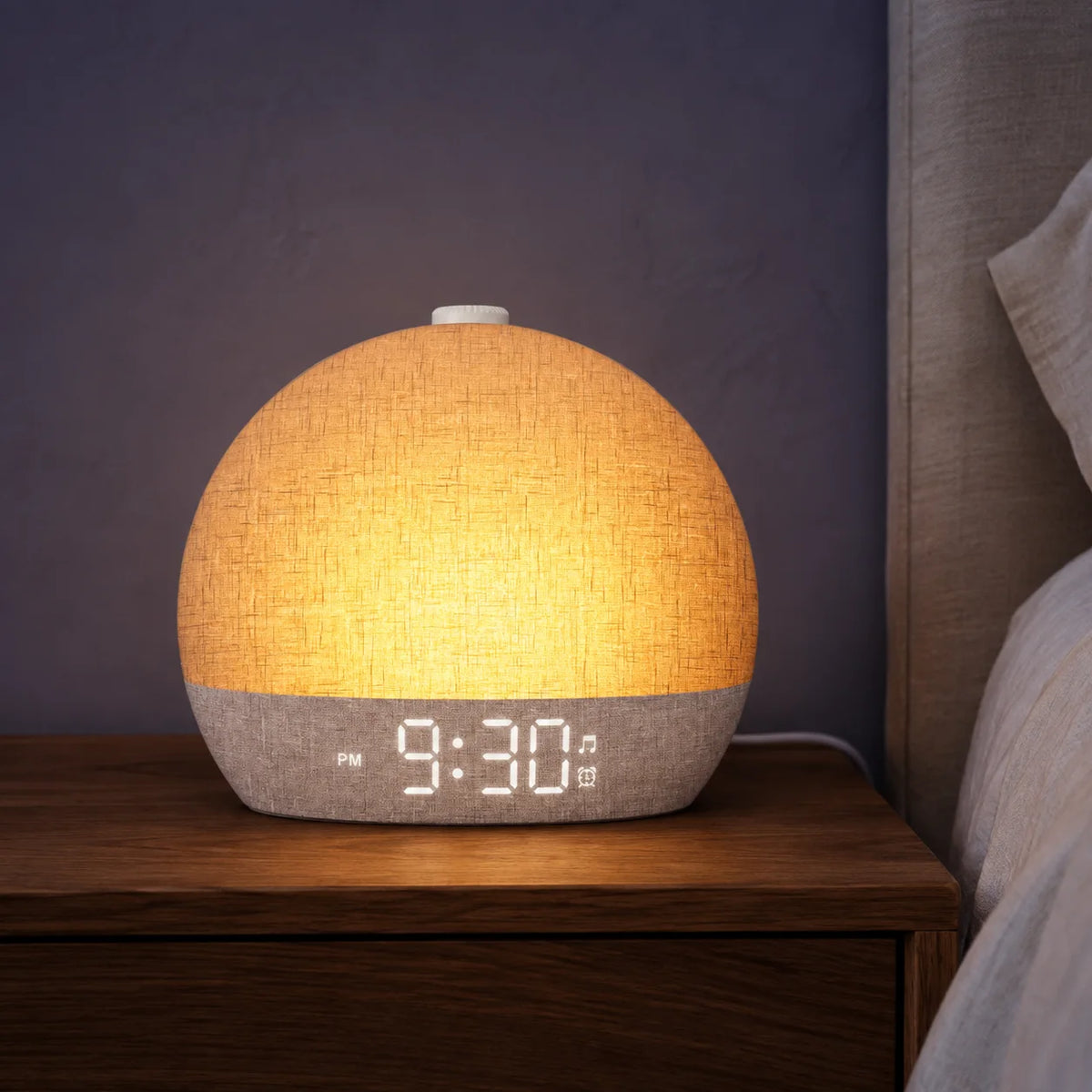 Amber sunrise alarm clock on a walnut bedside table at dusk.